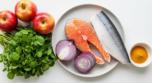 A vibrant flat lay of UK anti-histamine foods including red onions, apples, watercress, and a fillet of salmon, arranged on a clean, light kitchen surface.