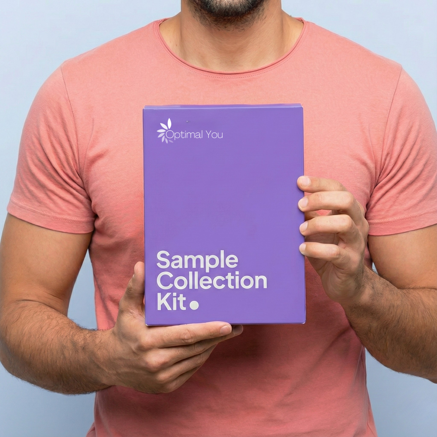 Person holding a purple 'Optimal You Sample Collection Kit' against a light blue background