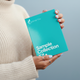 Person holding a teal 'Optimal You' sample collection kit against a light blue background wearing rings
